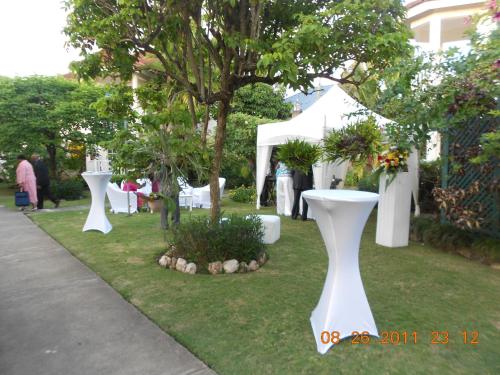 a garden with white tables and a tree in the grass at Pipers Cove Resort in Runaway Bay