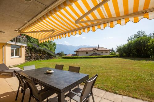 a patio with a table and chairs and a yard at Blonay Garden Apartment - Swiss Hotel Apartments in Blonay