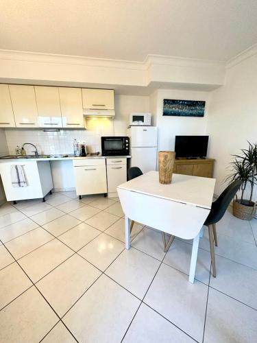 - une cuisine avec des appareils blancs, une table et des chaises dans l'établissement 1 BEDROOM Plein centre JUAN LES PINS, à Antibes