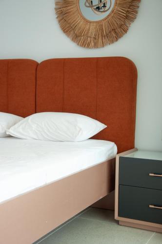 a bed with a wooden headboard and a clock on the wall at Seaview apartments in Ayios Elias