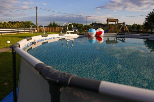 a swimming pool with two balls and a playground at Jej i Jego - Eleganckie domki z balią na wyłączność in Niewiesze