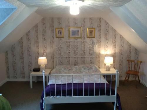 a bedroom with a bed in a attic with two lamps at The Old Bakery in Châteauneuf-du-Faou