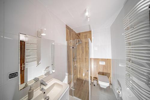 biała łazienka z umywalką i prysznicem w obiekcie Domek Góralski w mieście Piwniczna