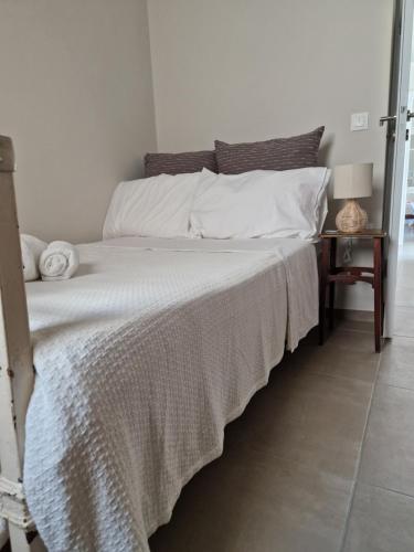 una camera da letto con un letto con lenzuola bianche e un tavolo di The Garden House a Città di Tinos