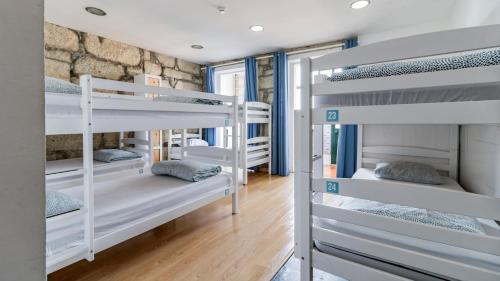 a room with four bunk beds and a stone wall at Invictus Hostel in Porto