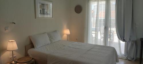a white bedroom with a bed and a window at Neaktion Apartments in Nikiti