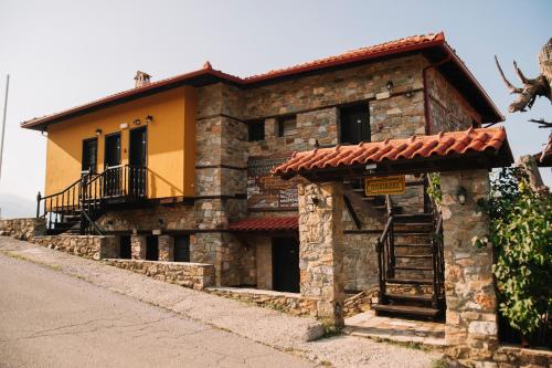 a stone house with a balcony on a street at Pliades Traditional Guesthouse in Palaios Panteleimon
