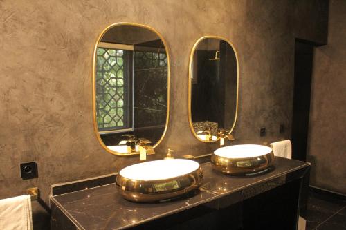 a bathroom with two sinks and two mirrors at Villa Le Petit Paradis Saly Boutique Hotel in Ngaparou