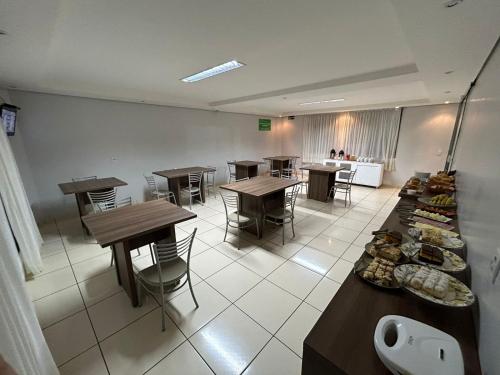 a room with tables and chairs and a kitchen at Vitória Hotel - Guaíra PR in Guaíra