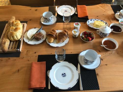 une table en bois recouverte d'assiettes, de tasses et de pâtisseries dans l'établissement Domaine de La Mazure, à La Chapelle-Basse-Mer