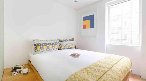 um quarto com uma grande cama branca e uma janela em Fitzrovia Apartment By Morethanstays em Londres