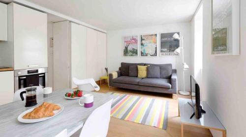 ein Wohnzimmer mit einem Sofa und einem Tisch in der Unterkunft Fitzrovia Apartment By Morethanstays in London