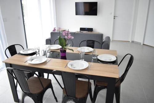 una mesa de madera con sillas y platos. en Maison climatisée accessible PMR en Argelès-Gazost