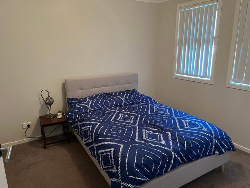 4BR House for Whole Family في Schofields: سرير لحاف من اللون الأزرق والأبيض في غرفة النوم