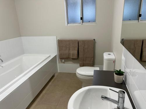a bathroom with a tub and a toilet and a sink at 4BR House for Whole Family in Schofields