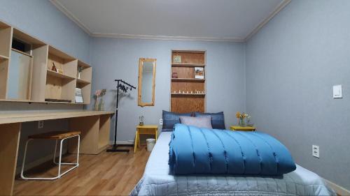 - une chambre avec un lit bleu et un bureau dans l'établissement Yachtie Inn Yudal, à Mokpo