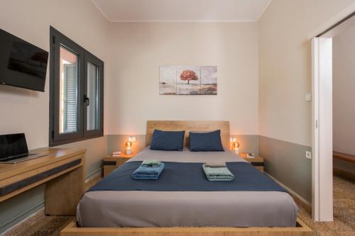 a bedroom with a bed with blue sheets and a television at Isabella's Hidden Gem House in Chania Town