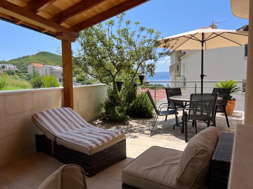 une terrasse avec une table, des chaises et un parasol dans l'établissement Apartments San Monte, à Podstrana