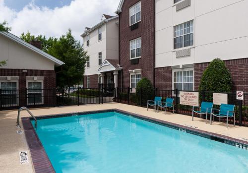 a swimming pool with chairs and a building at TownePlace Suites Dallas Arlington North in Arlington