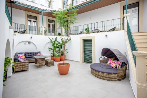 an outdoor patio with wicker furniture and plants at Guest House Jacarandá Faro in Faro