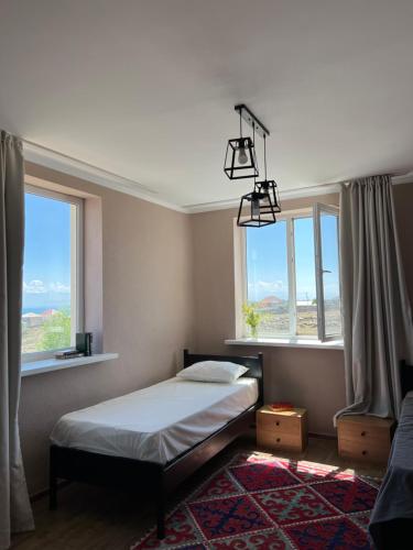 ein Schlafzimmer mit einem Bett und zwei Fenstern in der Unterkunft Guest house Hygge in Tscholponata