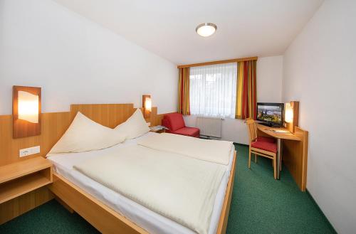 ツェル・アム・ゼーにあるGästehaus Rudolfoのベッドとテレビが備わるホテルルームです。
