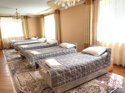 szereg łóżek w pokoju z oknami w obiekcie Guest house Ayperi w mieście Bokonbayevo