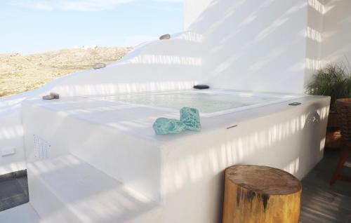 bañera de hidromasaje en un edificio blanco con un tronco de madera en Villa Ktima Lipsi - Jacuzzi & Stunning Sea Sunsets en Klouvas