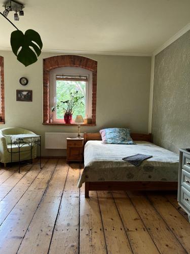 a bedroom with a bed with a wooden floor and a window at Przytulne Siedlisko in Jugowice