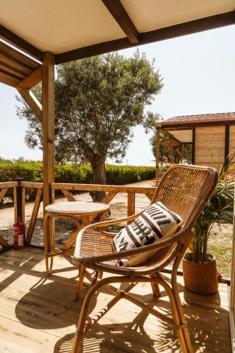 a wicker chair sitting on a deck with a table at Dreamsea Bungalows Alentejo in Porto Covo