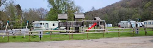 een park met een speeltuin met huizen en een glijbaan bij Nikita caravane in Aywaille
