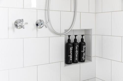 ‘Attunga’-1 min to Sovereign Hill, CBD, wifi, bath في بالارات: حمام من البلاط الأبيض مع زجاجات سوداء ومرآة