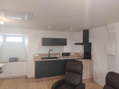 a kitchen with a sink and a counter with a microwave at Appartement plein centre in Broons