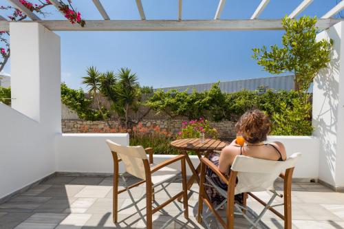 a woman sitting at a table on the balcony of a house at Christiana Hotel in Ambelas