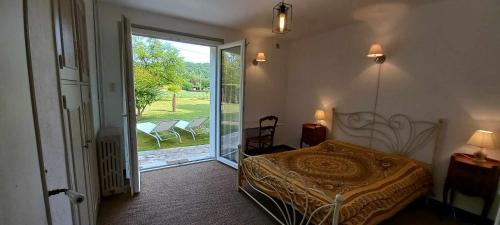 um quarto com uma cama e uma porta para um pátio em Gîte près de Sarlat avec jardin et salon de massages em Carsac-Aillac