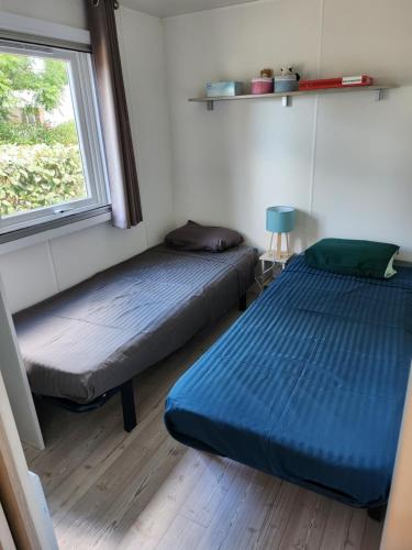twee bedden in een kleine kamer met een raam bij camping sable du midi 4 etoiles in Valras-Plage