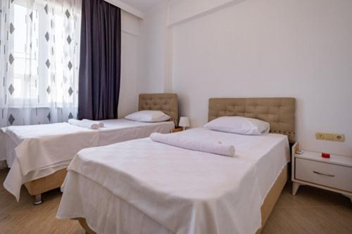 - une chambre avec 2 lits avec des draps blancs et une fenêtre dans l'établissement ASSOS APART BELEK, à Belek