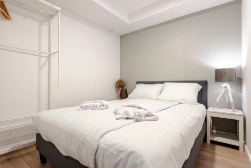 een witte slaapkamer met een groot bed met handdoeken erop bij Summer House in Zandvoort
