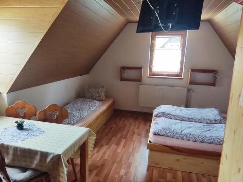 um quarto no sótão com 2 camas e uma mesa em Penzion Leštiny em Dolný Kubín
