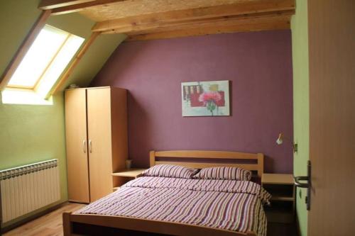 ein Schlafzimmer mit einem Bett und einer lila Wand in der Unterkunft Apartman Maja in Gračac