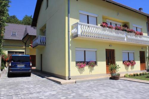 a blue truck parked next to a yellow house at Apartman Maja in Gračac