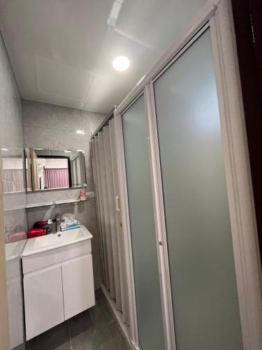 a bathroom with a shower and a sink and a mirror at Tamshui Homestay in Tamsui