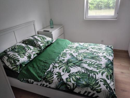 1 dormitorio con 1 cama con edredón verde y blanco en Domek letniskowy w Sitnie, en Sitno