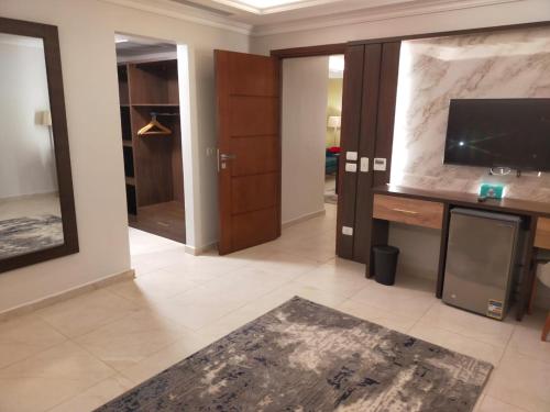 a living room with a tv and a desk with a television at Grand Plaza Hotel & Resort in Qaryat ash Shamālī