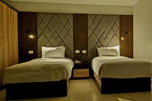 a bedroom with two beds and a headboard at Grand Plaza Hotel & Resort in Qaryat ash Shamālī