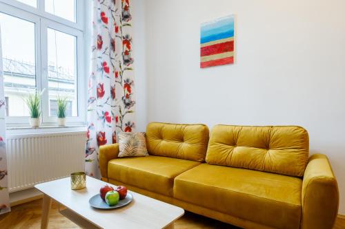a living room with a yellow couch and a table at OK LUX Apartments in Krakow