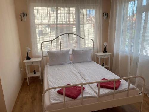 a bedroom with a white bed with two windows at Къща за гости Германови in Obzor