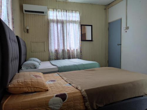 two beds in a small room with a window at Mgh Marang guest house in Kampong Kijing