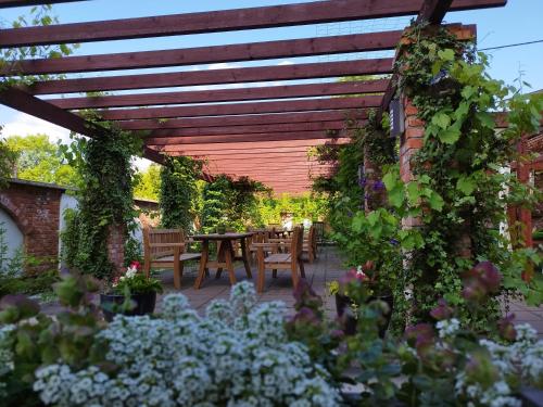 a pergola in a garden with a table and chairs at Noclegi Szymrych in Chełmsko Śląskie