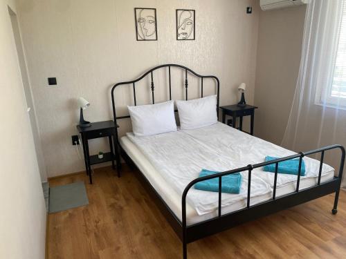 a bedroom with a bed with a black frame and two tables at Къща за гости Германови in Obzor